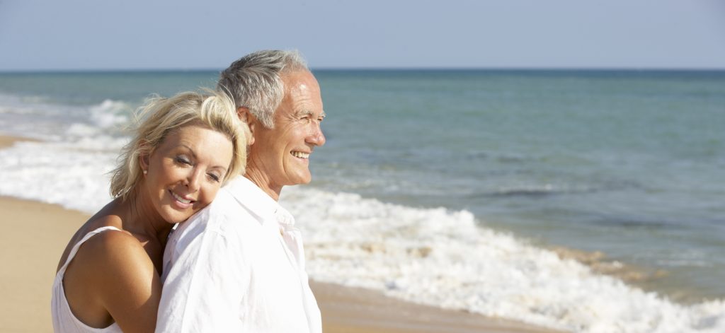 an older couple smiling and looking out at the sea